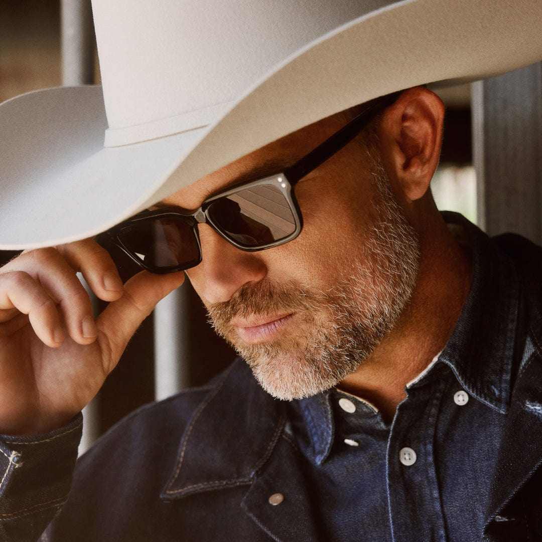 John Dutton wearing DIFF x Yellowstone polarized black sunglasses with white cowboy hat and denim shirt